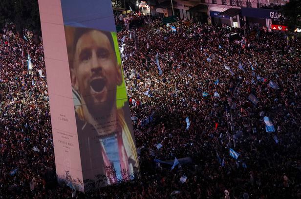 18일(현지시각)  아르헨티나 부에노스아이레스에서 리오넬 메시의 이미지가 걸린 광장에 모인 시민들이 월드컵 승리를  기뻐하고 있다./로이터 연합뉴스