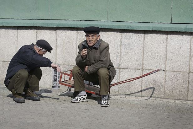 북한 평양에서 노인 남성들이 한 건물 앞에서 담배를 피우며 쉬고 있다/AP 연합뉴스