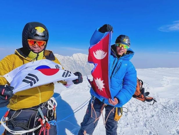 Korea's representative mountaineer Um Hong-gil (left), who finally reached the summit of the first peak in the Jugal Himalayas, and Nepal's representative mountaineer Lakpa Dendi are posing at the summit holding the Korean national flag and the Nepali flag, respectively. /Jugal Himalayan Expedition