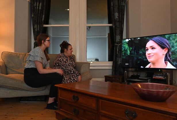 영국 리버풀에 거주하는 주민들이 8일(현지 시각) 해리 왕자와 메건 마클 왕자비가 CBS방송에 출연해 인터뷰 하는 모습을 지켜보고 있다. 인터뷰는 미국에서 방송된 지 하루만인 이날 영국 TV에서도 소개됐다. /AFP 연합뉴스