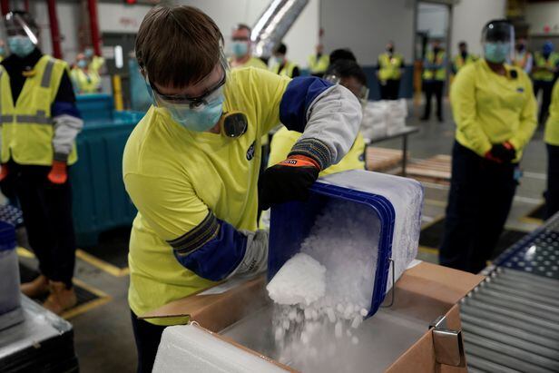 13일 미국 제약사 화이자의 직원들이 미시간주 글로벌 서플라이 캘러머주 의약품 생산 공장에서 생산된 코로나 백신 상자에 드라이 아이스를 넣어 포장하고 있다./로이터 연합뉴스