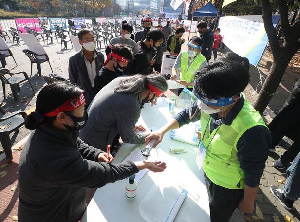 14일 오후 서울 영등포구 여의도공원 앞에서 전국노동자대회 집회 참가자들이 체온 측정을 받고 있다.  /연합뉴스