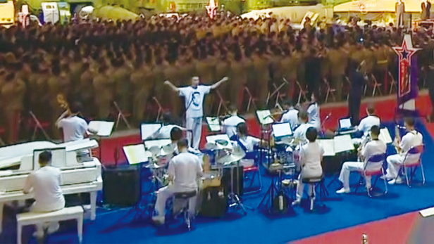 12일 북한에서 열린 국방발전전람회에서 실내 연주를 하는 악단의 지휘자와 단원들이 모두 김정은 얼굴이 그려진 티셔츠를 입고 연주를 하는 이례적인 모습이 연출되었다./조선중앙TV