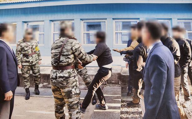 2019년 11월 판문점을 통해 강제 북송되는 북한 어민이 군사분계선(MDL) 선상에서 북한군에게 두 팔이 잡히자 엉덩이를 뒤로 빼며 저항하는 모습. /통일부 