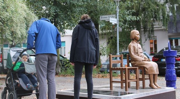 지난달 25일(현지 시각) 독일 수도 베를린에 설치된 '평화의 소녀상'에 쓰인 비문을 지나가던 시민들이 읽고 있다. /연합뉴스