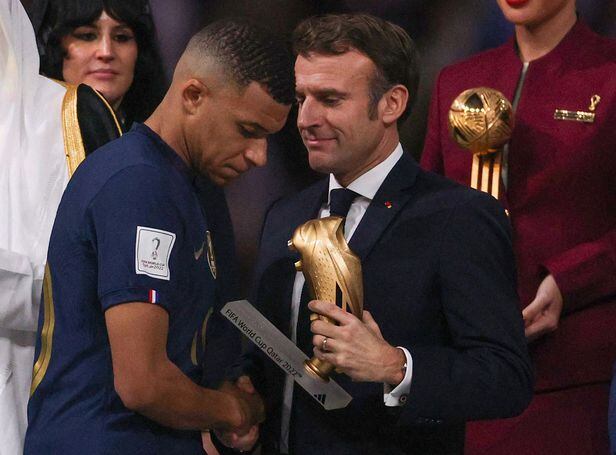 킬리안 음바페(왼쪽)가 19일(한국시각) 2022 카타르 월드컵 득점왕에 올라 시상식에서 에마뉘엘 마크롱 프랑스 대통령으로부터 골든부트 트로피를 수여받고 있다. 음바페의 표정은 굳어 있다. /AFP 연합뉴스