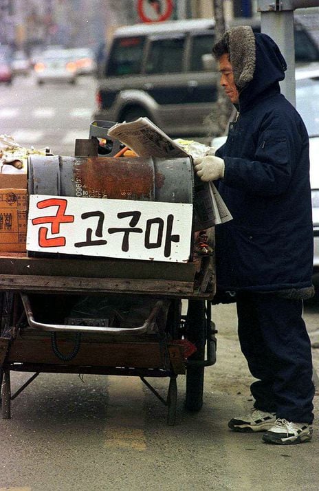 1998년 군고구마가 무럭무럭 익어가는 수레 앞에서
신문을 펼쳐들고 열심히 읽고 있는 군고구마 장수.