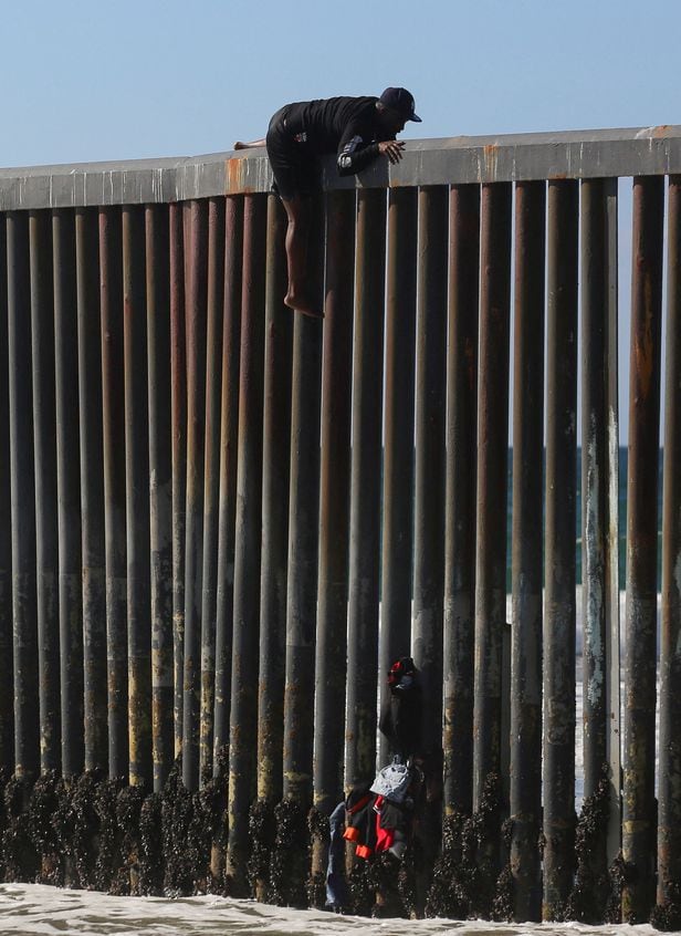 지난 2일(현지 시각) 미국과 멕시코의 접경지대인 티후아나에 세워진 장벽을 중남미 이민자들이 넘고 있다. 최근 조 바이든 미국 대통령은 장벽 설립을 다시 시작한다고 했다. /로이터
