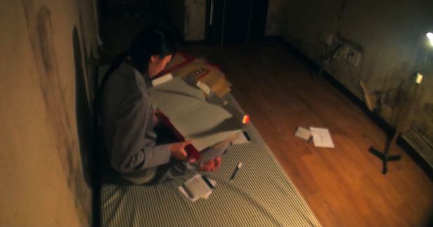 피의 게임 한 참가자가 음침한 지하방에서 피자 상자를 접고 있다. /'피의 게임'